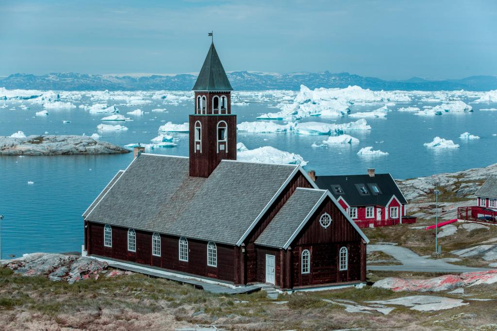 Die Zion-Kirche in Ilulissat mit der Diskoinsel im Hintergrund