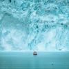A small passenger boat in front of the huge glacier wall at the Eqi glacier in Greenland