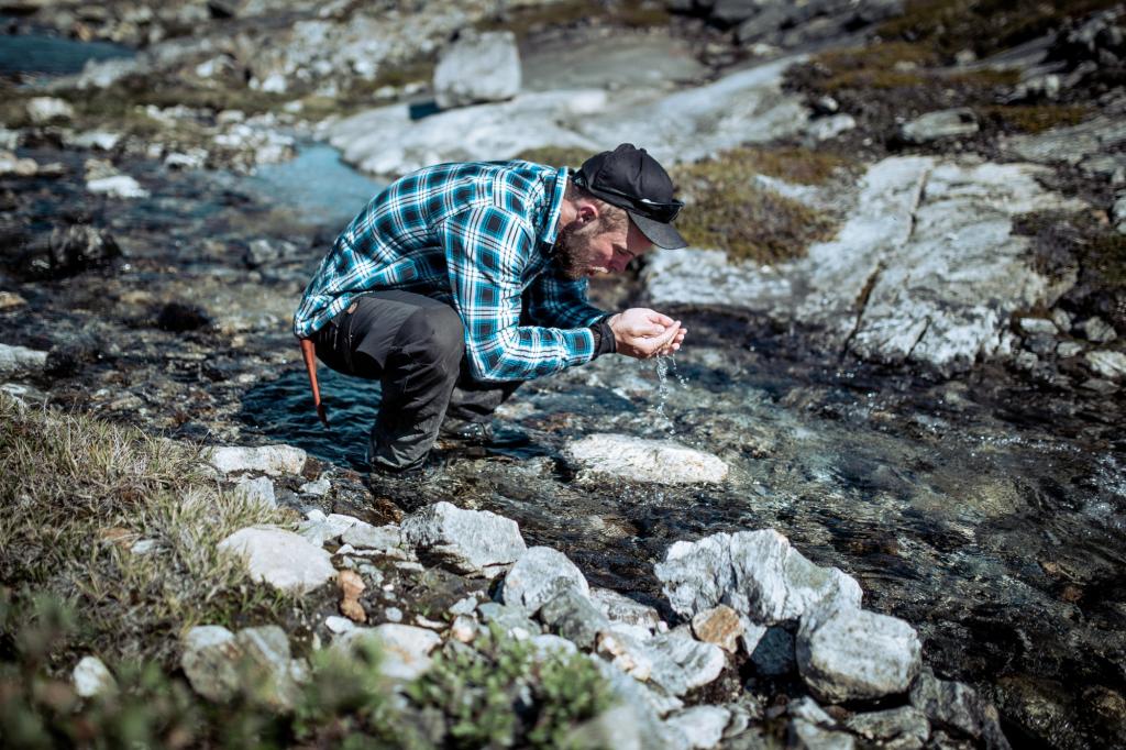 A hiker in East Greenland drinking pure, fresh water from a stream